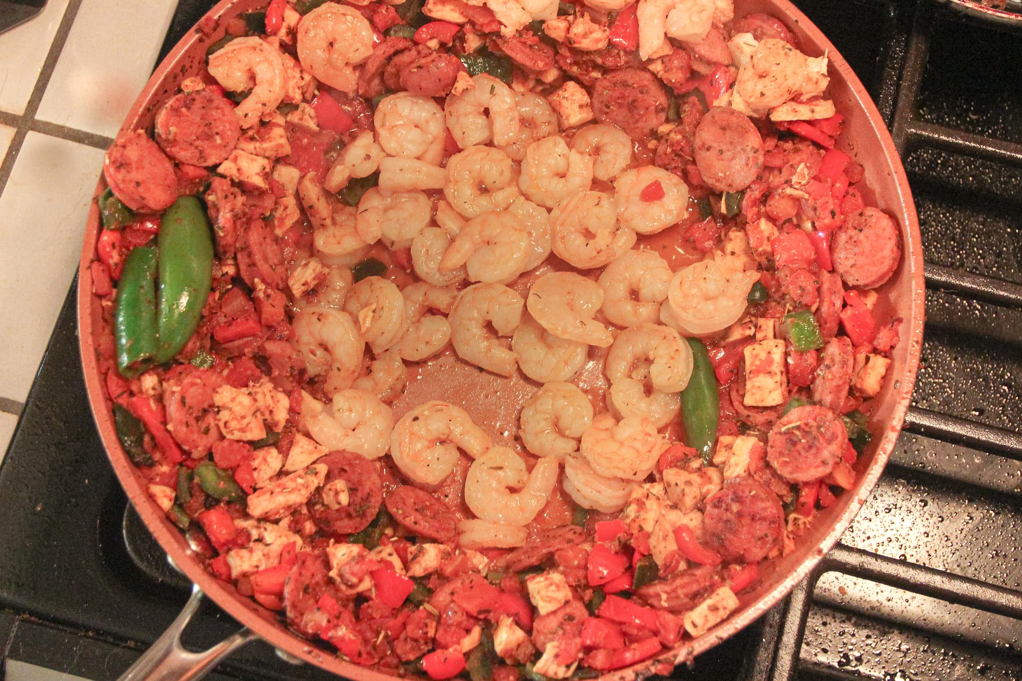 One-Pot Easy Keto Jambalaya shrimp cooking in the skillet with sausage, chicken, vegetables and cajun spices.