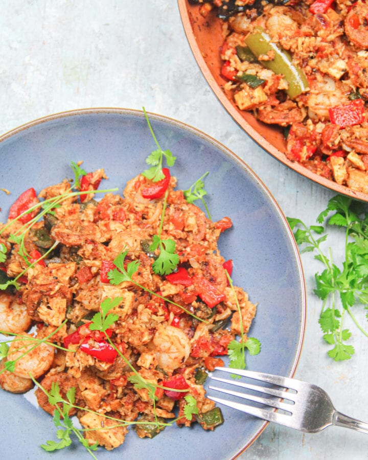 One-Pot Easy Keto Jambalaya plated and topped with cilantro with skillet in the background.